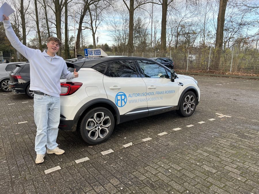 Geslaagde leerling met de armen in de lucht naast de lesauto