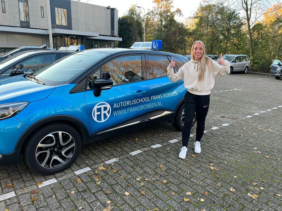 Geslaagde leerling bij de blauwe lesauto in Schiedam