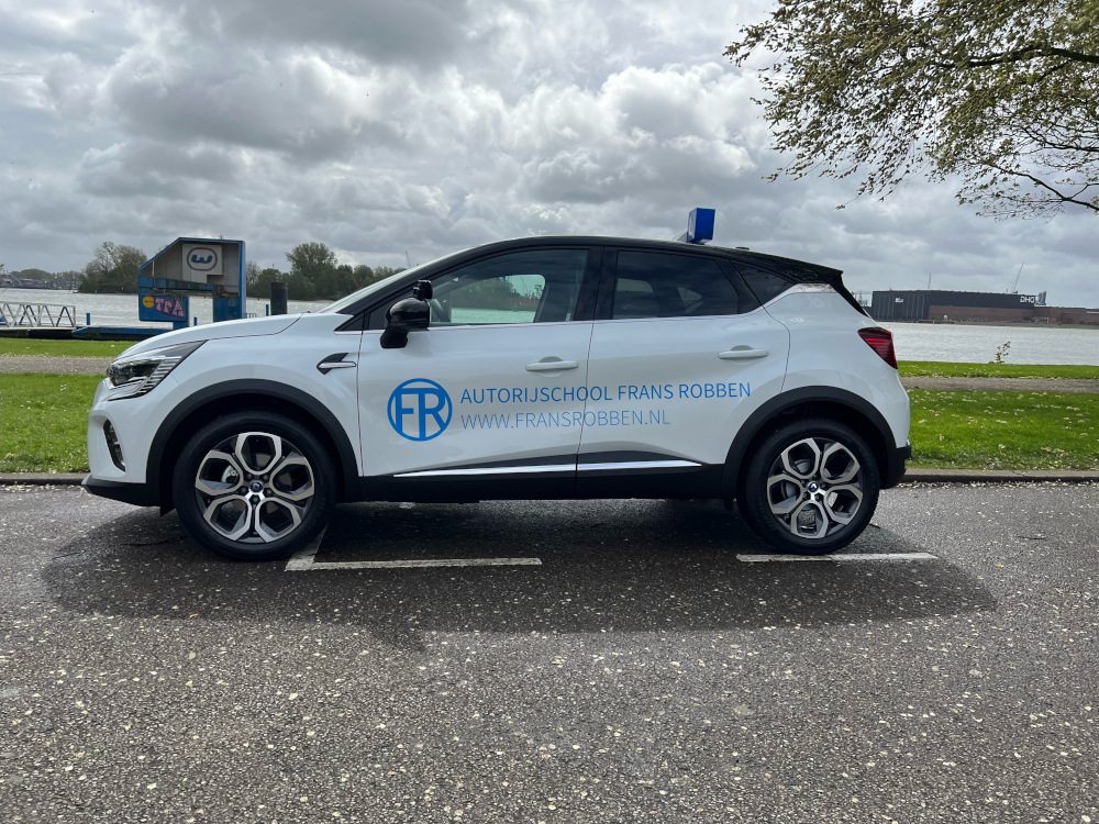 De witte Renault Captur van Autorijschool Frans Robben met het blauwe L-bord, langs de Nieuwe Maas bij Schiedam